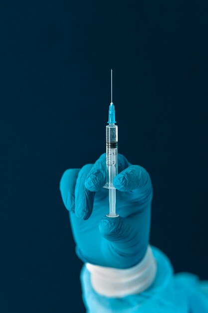 Arzt in Spezialausrüstung, der den Covid-19-Impfstoff hält
