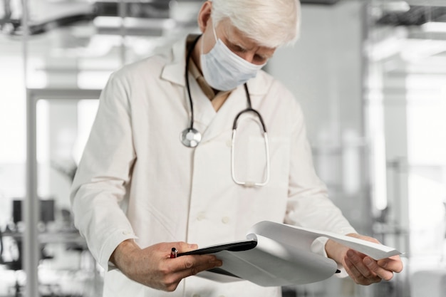 Arzt mit medizinischer Maske, der seine Notizen überprüft