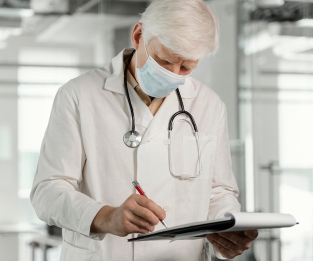 Arzt mit medizinischer Maske, der seine Notizen überprüft