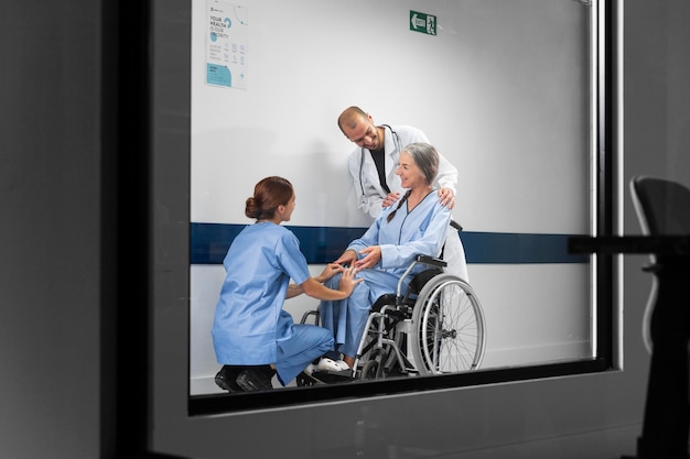 Arzt und Krankenschwester helfen einem Patienten im Rollstuhl