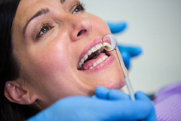 Arzt untersucht weibliche Patientenzähne mit dem Mundspiegel