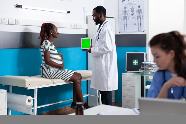 Arzt zeigt der Frau Tablet mit vertikalem grünem Bildschirm