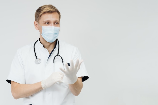 Arzt zieht Handschuhe an und trägt medizinische Maske