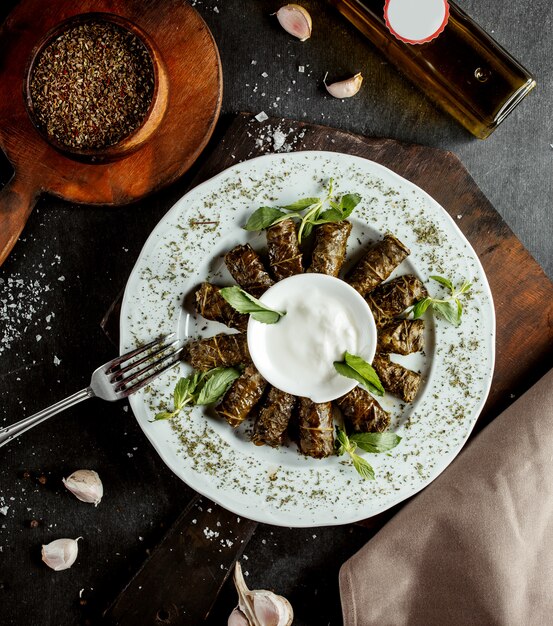 Aserbaidschanische lange eingewickelte Weinblätter Dolma, garniert mit Joghurt und getrockneten Minzblättern