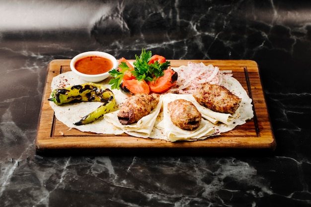 Aserbaidschanischer Rindfleischgrillkebab serviert auf Lavash mit gegrilltem Pfeffer und Tomaten.