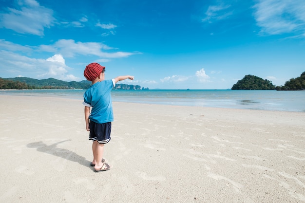 Asian Boy zu Fuß am Strand im Freien Meer und blauer Himmel