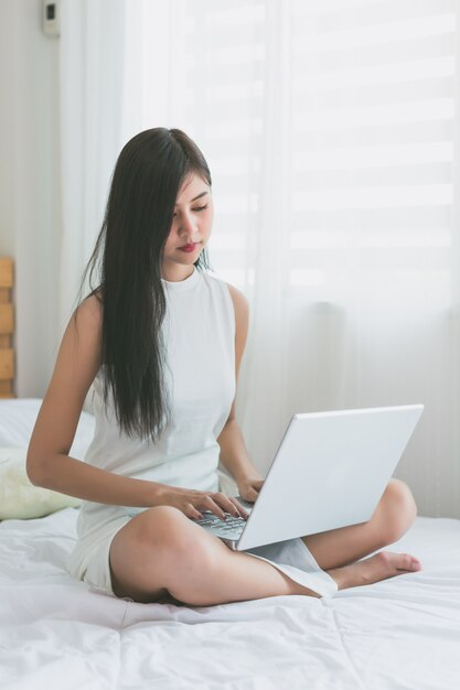 Asiatinnen spielen mit Laptop im Schlafzimmer