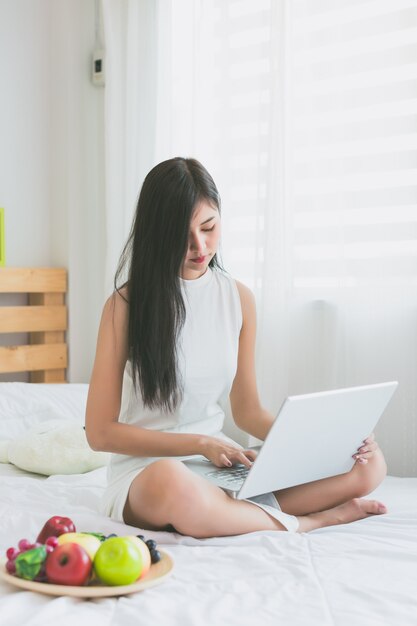 Asiatinnen spielen mit Laptop im Schlafzimmer