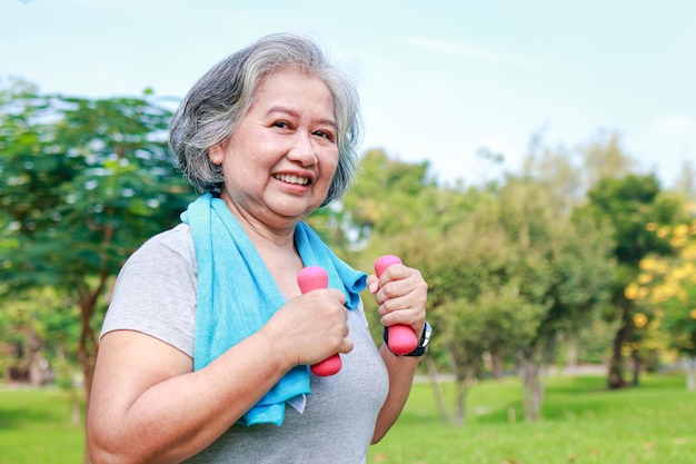 Asiatische ältere frau trainiert morgens im park, sie lächelt glücklich gesunder körper. konzept der gesundheitsversorgung für senioren, um gesund zu sein