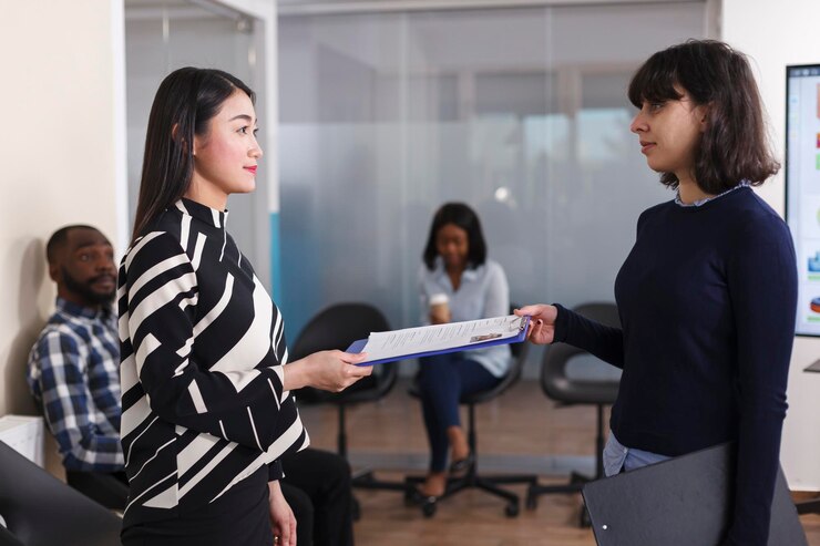 Kostenlose Foto asiatische arbeitslose frau, die dem personalleiter einen lebenslauf gibt, um interviewt zu werden. verschiedene leute im wartezimmer einer startup-agentur sprechen über karrierechancen und rekrutierungsverfahren