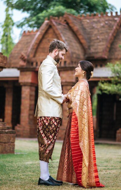 Asiatische Braut und kaukasischer Bräutigam haben romantische Zeit mit Thailand-Kleid