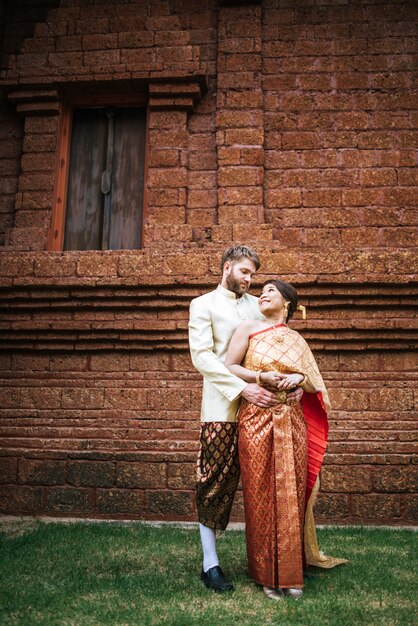 Asiatische Braut und kaukasischer Bräutigam haben romantische Zeit mit Thailand-Kleid