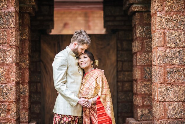 Asiatische Braut und kaukasischer Bräutigam haben romantische Zeit mit Thailand-Kleid