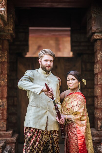 Asiatische Braut und kaukasischer Bräutigam haben romantische Zeit mit Thailand-Kleid