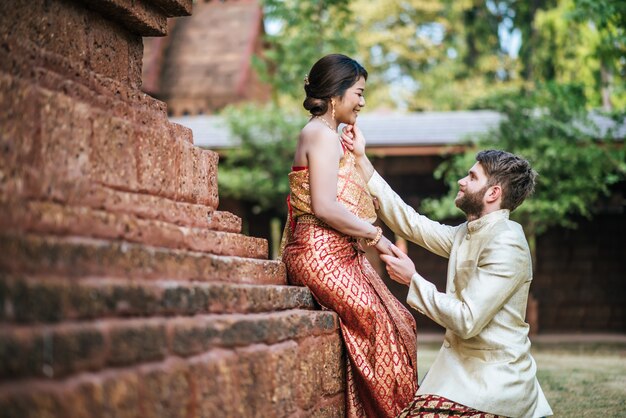 Asiatische Braut und kaukasischer Bräutigam haben romantische Zeit mit Thailand-Kleid