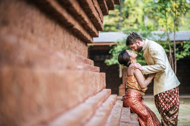 Asiatische Braut und kaukasischer Bräutigam haben romantische Zeit mit Thailand-Kleid