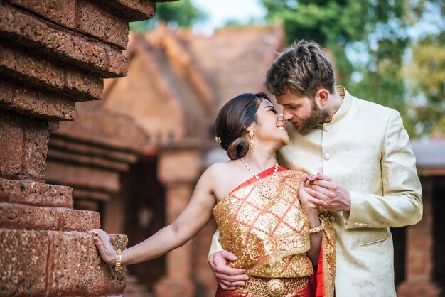 Asiatische Braut und kaukasischer Bräutigam haben romantische Zeit mit Thailand-Kleid