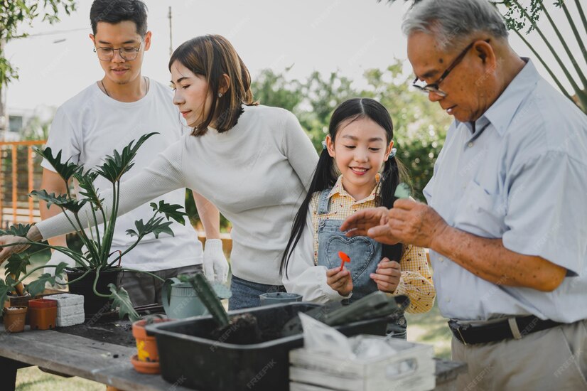 Asiatische familie, die zu hause baum im garten pflanzt
