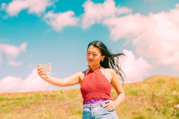 Asiatische Frau, die auf dem Gebiet fotografiert