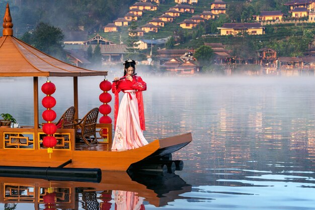 Asiatische Frau, die chinesisches traditionelles Kleid auf Yunan-Boot bei Ban Rak thailändischem Dorf in Mae Hong Sohn Provinz, Thailand trägt