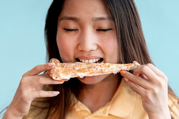 Asiatische Frau, die ein Stück Pizza Nahaufnahme isst