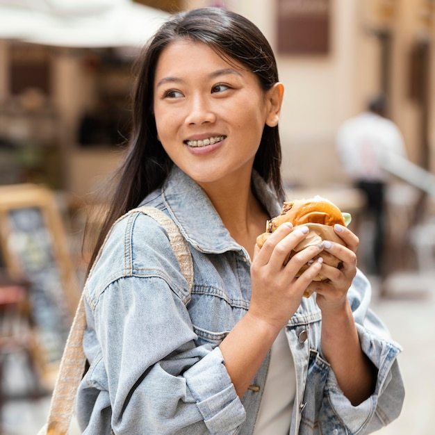 Asiatische Frau, die glücklich ist, nachdem sie Straßenlebensmittel gekauft hat