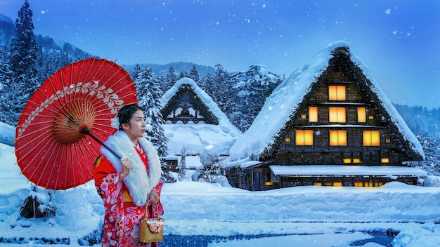 Kostenloses Foto asiatische frau, die traditionellen japanischen kimono am shirakawa-go-dorf im winter, japan trägt.