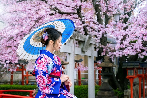 Asiatische Frau, die traditionellen japanischen Kimono und Kirschblüte im Frühjahr, Kyoto-Tempel in Japan trägt.