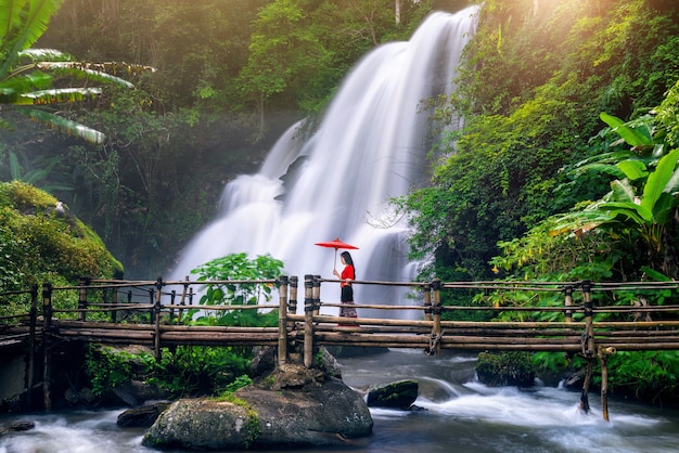 Asiatische Frau, die traditionelles thailändisches Kleid Kostüm entsprechend thailändischer Kultur am Pha dok siew Wasserfall in Chiang Mai Thailand trägt