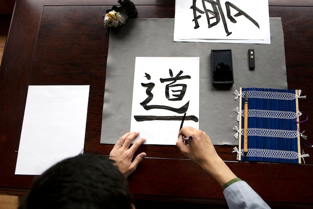 Asiatische Frau, die zuhause japanische Handschrift übt