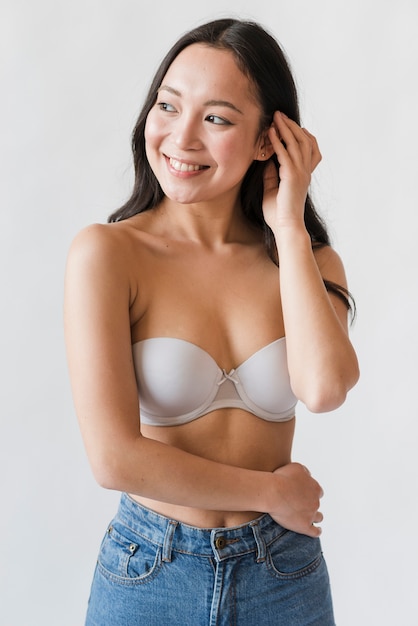 Asiatische Frau im Büstenhalter und in den Jeans