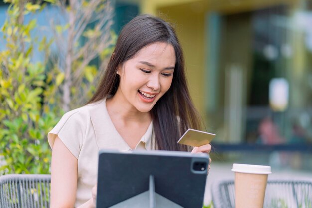 Asiatische Frau kauft online und bezahlt mit KreditkarteFrau sitzt im Café im Freien und genießt den Wochenendurlaub Online-Shopping auf dem Smartphone und mobile Zahlung mit Kreditkarte