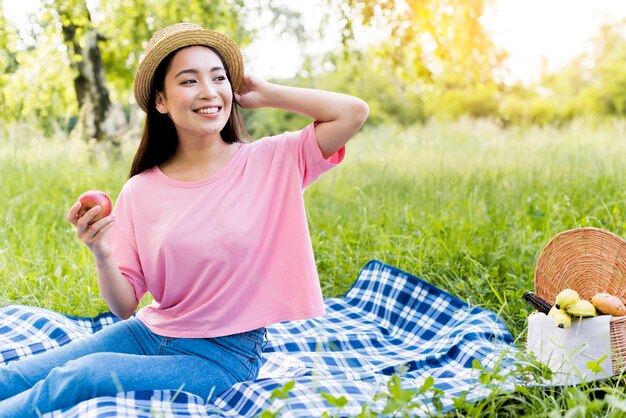 Asiatische Frau mit dem Apfel, der auf Decke sitzt