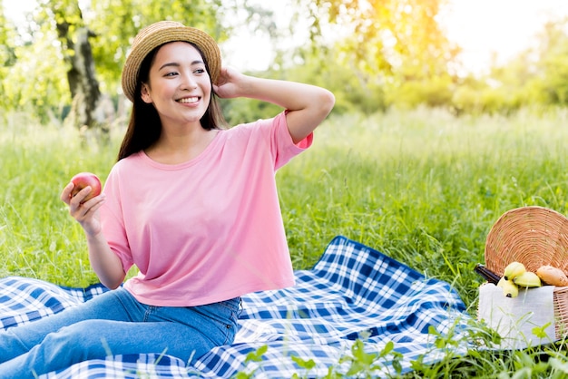 Asiatische Frau mit dem Apfel, der auf Decke sitzt