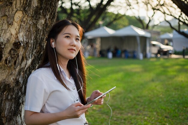 Asiatische Frau mit Tablette und Musik hören