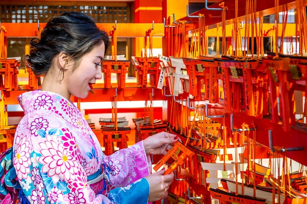 Asiatische Frauen, die japanischen traditionellen Kimono tragen, der das schöne in Fushimi Inari-Schrein in Kyoto, Japan besucht