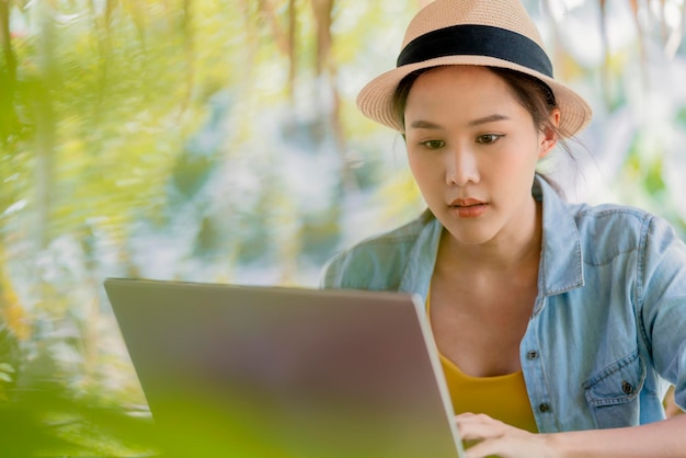 Asiatische freiberufliche digitale normadische tausendjährige gen y lebensstil entspannt lässiges arbeiten mit laptop im freien auf dem balkon in der nähe des strandes asiatische frau, die überall arbeitet neuer lebensstil arbeiten während der reise