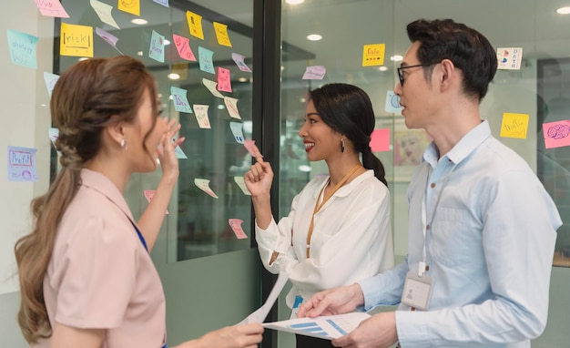 Asiatische Geschäftsleute treffen sich im Büro und verwenden Post-It-Notizen, um Ideen auszutauschen Brainstorming-Konzept