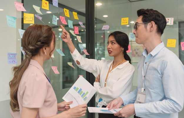 Asiatische Geschäftsleute treffen sich im Büro und verwenden Post-It-Notizen, um Ideen auszutauschen Brainstorming