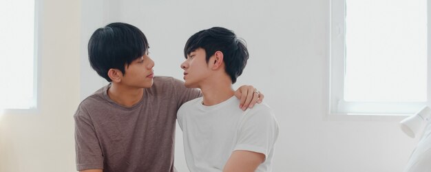 Asiatische homosexuelle Paare, die zu Hause auf Bett küssen. Junge asiatische LGBTQ + Männer, die glücklich sind, entspannen sich, verbringen zusammen romantische Zeit, nachdem sie morgens im Schlafzimmer zu Hause aufgewacht sind.