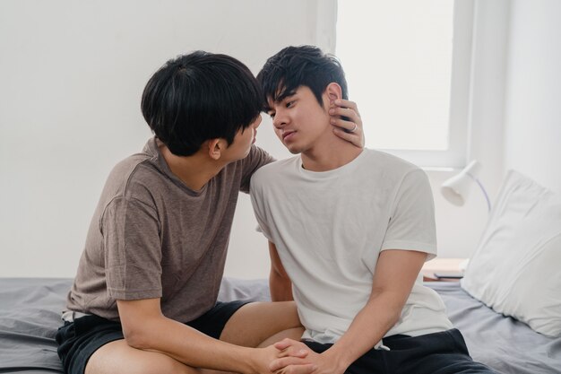 Asiatische homosexuelle Paare, die zu Hause auf Bett küssen. Junge asiatische LGBTQ + Männer, die glücklich sind, entspannen sich, verbringen zusammen romantische Zeit, nachdem sie morgens im Schlafzimmer zu Hause aufgewacht sind.