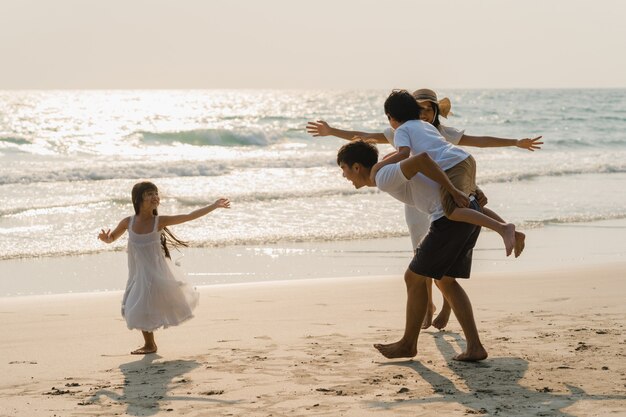Asiatische junge glückliche Familie genießen abends Urlaub am Strand. Vater, Mutter und Kind entspannen sich beim Spielen in der Nähe des Meeres bei Sonnenuntergang während des Reiseurlaubs. Lifestyle Reise Urlaub Urlaub Sommer Konzept.