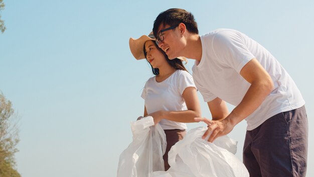 Asiatische junge glückliche Familienaktivisten, die Plastikmüll am Strand sammeln. Freiwillige aus Asien helfen dabei, die Natur sauber zu halten und Müll aufzuheben. Konzept über Umweltschutzprobleme.