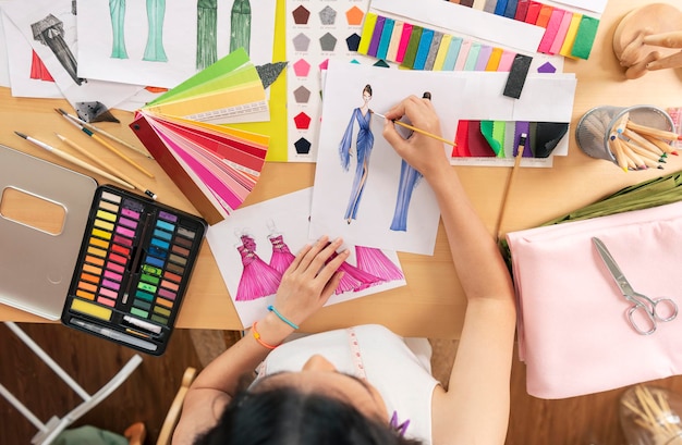 asiatische Modedesigner-Zeichnungsskizzen für neue Kollektion auf Draufsicht des Schreibtischbüros