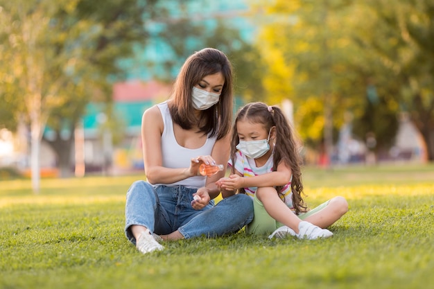 Asiatische Mutter und Tochter mit Desinfektionsmittel außerhalb