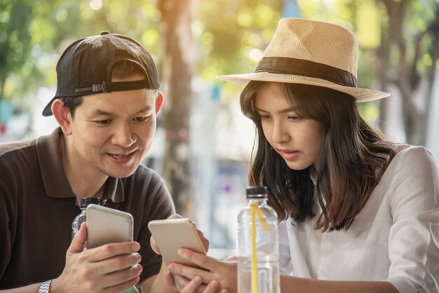 Asiatische Paare genießen, an der Kaffeestube sitzend zu reisen
