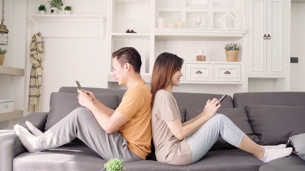 Asiatische Paare unter Verwendung des Smartphone überprüfen Social Media im Wohnzimmer zu Hause
