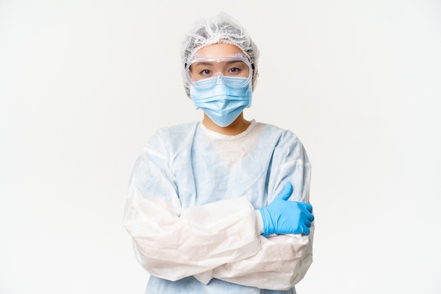 Asiatische Ärztin oder Krankenschwester in PPE, persönliche Schutzausrüstung vor Coronavirus, bereit und selbstbewusst, weißer Hintergrund.