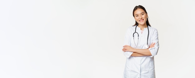 Asiatische Ärztin Ärztin in medizinischer Uniform mit Stethoskop-Kreuzarmen auf der Brust lächelnd und lo