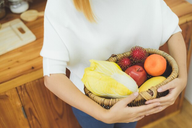 Asiatische Schönheit, die Obst und Gemüse in der Küche an ihrem Haus hält